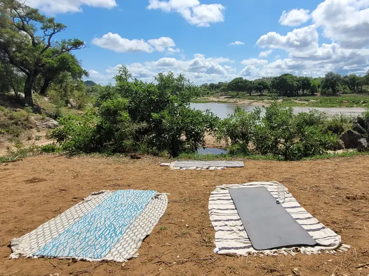 Deux tapis de yoga posés face à une rivière, au cœur du bush africain