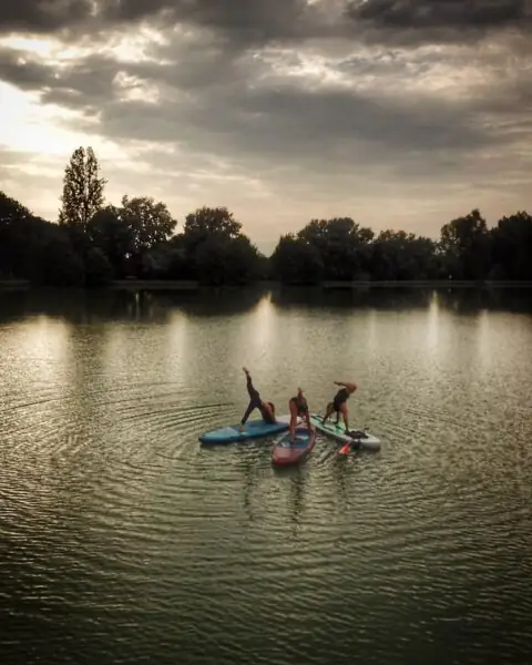Deux silhouettes en équilibre sur des paddles, sur une eau calme au crépuscule